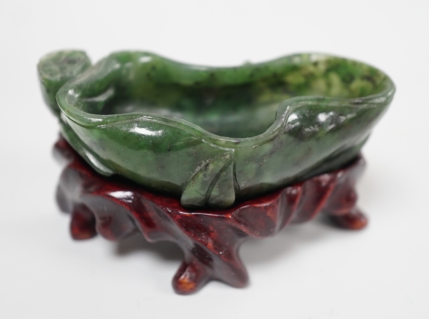 A Chinese spinach green jade 'lotus' brushwasher, 19th century, 6.8cm, wood stand